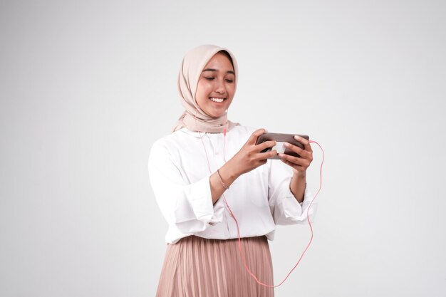 Uma mulher vestindo um hijab está jogando um jogo com um telefone.