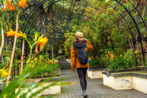 Foto uma mulher vestindo uma jaqueta marrom e um chapéu de palha caminha por um jardim