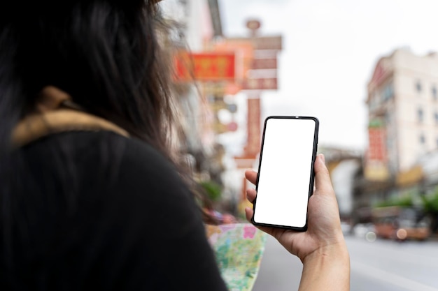 Uma mulher viajando na cidade chinesa de bangkok tailândia usa um smartphone para tirar uma foto segurando um smartphone