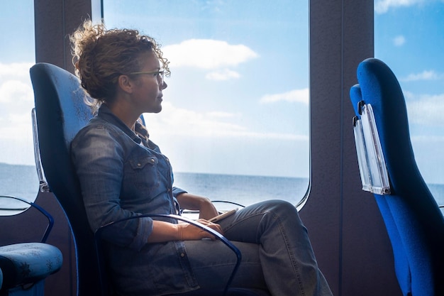Foto uma mulher viajando sozinha dentro de um cruzeiro de balsa com vista para o mar e céu azul conceito de transporte e viagem de negócios mulheres admiram a natureza ao ar livre sentada no assento da marinha