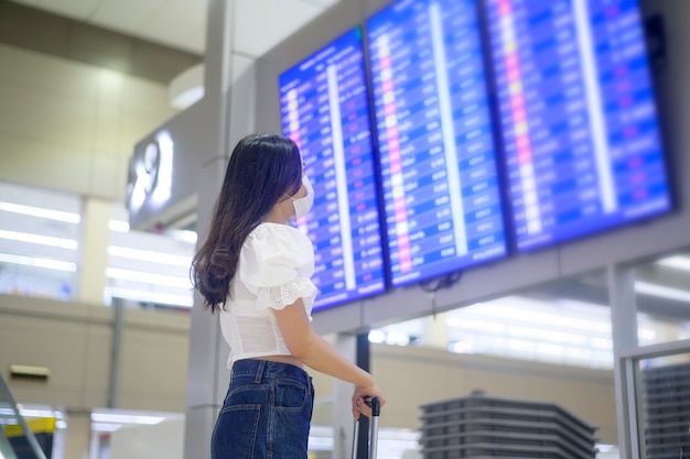 Uma mulher viajante está usando máscara protetora no aeroporto internacional, viajando sob a pandemia de covid-19