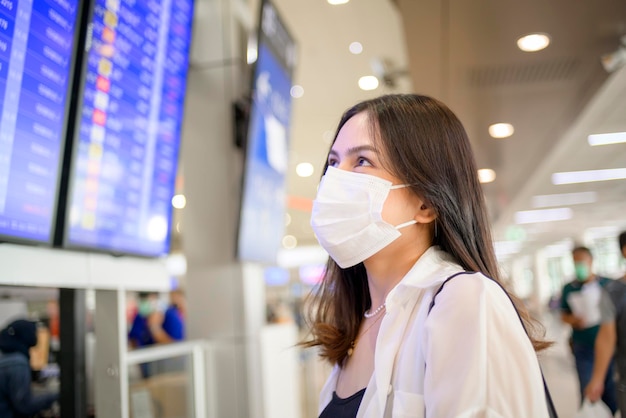 Uma mulher viajante está usando máscara protetora no aeroporto internacional