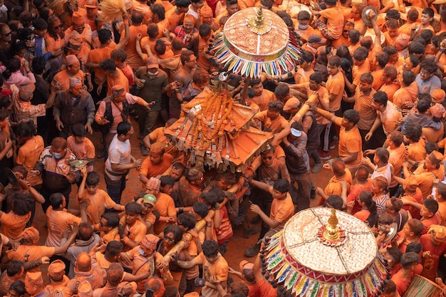 Uma multidão de pessoas está reunida em torno de um objeto decorado de forma colorida.