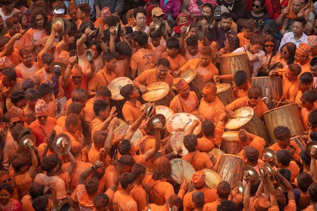 Uma multidão de pessoas está reunida em torno de um templo pintado de laranja.