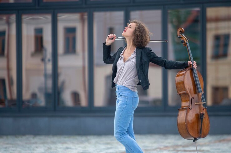 Foto uma músico com um violoncelo na rua.