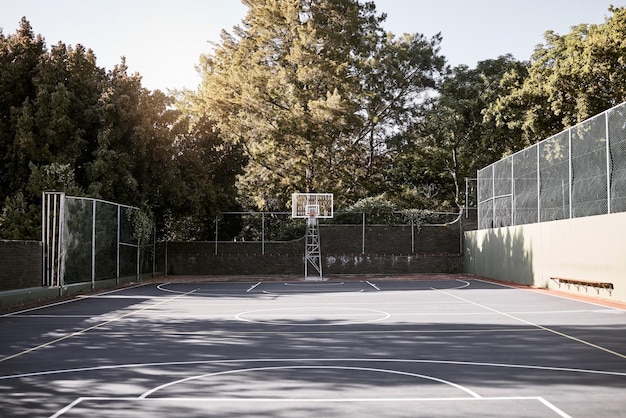 Uma natureza morta vazia de uma quadra de basquete em um dia ensolarado com marcação branca com aro e rede Um campo esportivo ou quadra em um local do clube para treinamento de práticas ativas e atividades de lazer ao ar livre