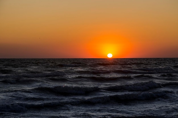 Uma noite de pôr do sol laranja sobre o mar Negro com grandes ondas escuras Kinburn Foreland shore Ucrânia