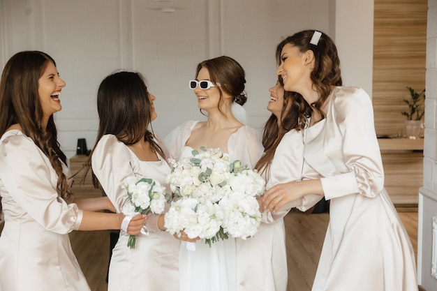 Uma noiva e suas damas de honra estão todas usando vestidos brancos e segurando um buquê de flores brancas.