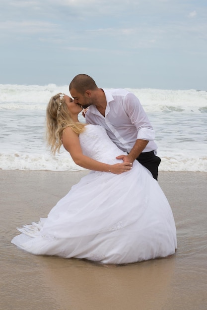 Uma noiva e um noivo atraentes se casando na praia