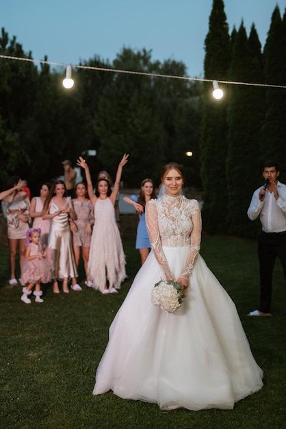 Uma noiva em um vestido branco joga um buquê de casamento