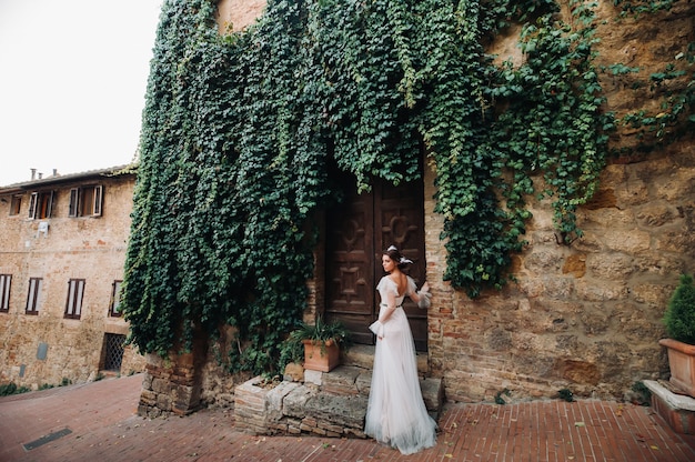 Uma noiva em um vestido branco na cidade velha de San Gimignano. Uma garota anda pela cidade em Italy.Tuscany.