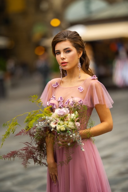 Uma noiva em um vestido rosa com um buquê está no centro da cidade velha de Florença, na Itália.