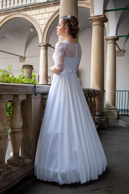 Uma noiva está em uma varanda em um vestido branco