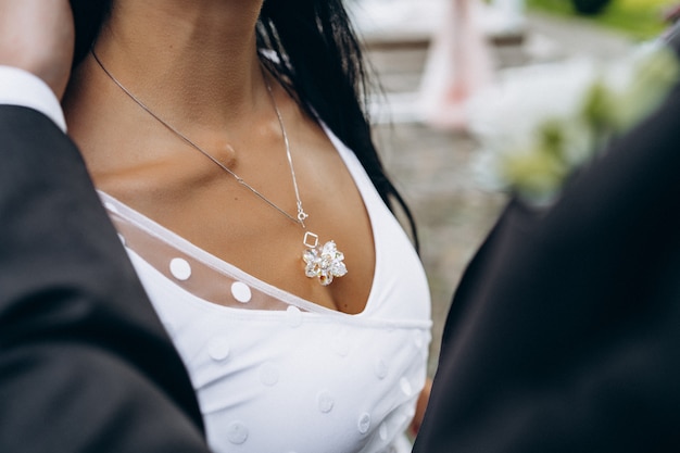 Uma noiva muito linda em um vestido de noiva abraça seu homem elegante. casal. vestido de casamento, publicidade de jóias, salão de casamento. faixa de casamento.