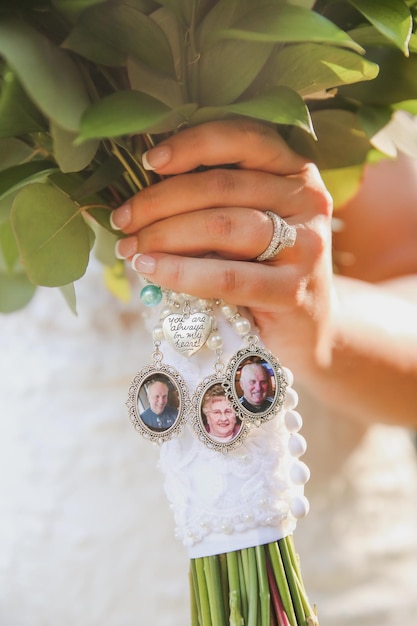 Uma noiva segura um buquê de flores com as fotos de sua família.