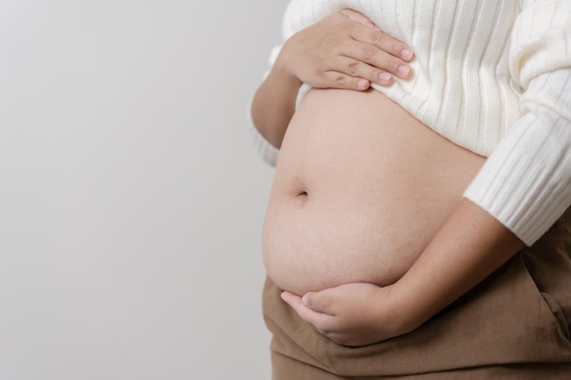 Uma obesidade carregando sua barriga gordinha para mostrar o conceito de mulher gorda insalubre