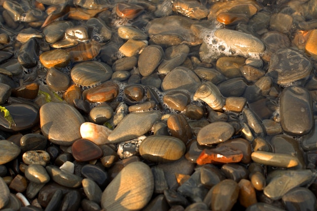 Uma onda do mar transparente pura rola sobre a costa de seixos rochosos o conceito de descanso e viagem tranquilidade relaxamento e reflexão em um dia quente de verão closeup