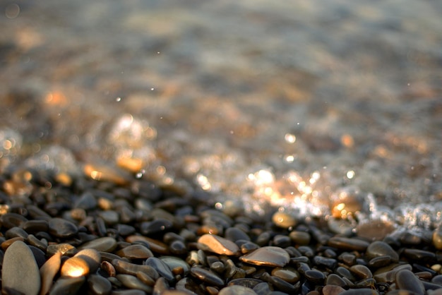 Uma onda do mar transparente rola sobre uma praia de seixos, recreação e viagens, desfocagem, bokeh.