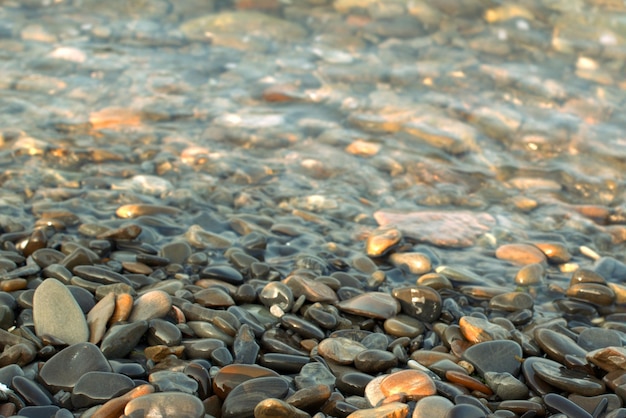 Uma onda do mar transparente rola sobre uma praia de seixos, recreação e viagens, desfocagem, bokeh.