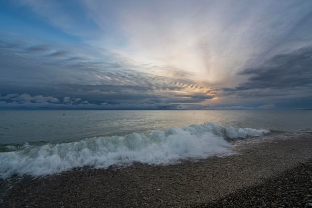 Foto uma onda entrante na costa do mar negro contra o céu do pôr-do-sol sochi território de krasnodar rússia