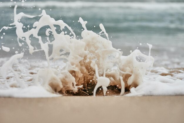 Foto uma onda está a bater numa praia com o oceano ao fundo