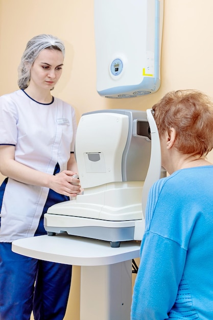 Uma optometrista menina examina os olhos de um paciente usando equipamentos modernos especiais