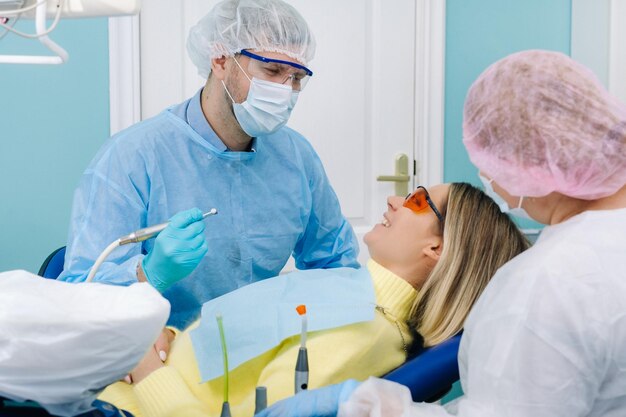 Uma paciente do sexo feminino em óculos dentários trata os dentes no dentista com obturações dentárias de luz ultravioleta