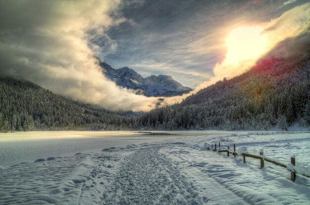 uma paisagem coberta de neve com um lago e montanhas ao fundo