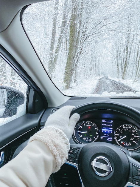 Uma paisagem de neve fora das mãos femininas no volante