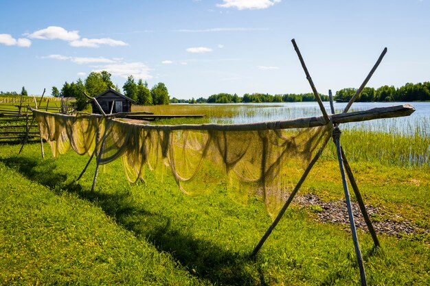 Uma paisagem rural de verão pendurando redes de pesca secando ao ar livre na margem do lago