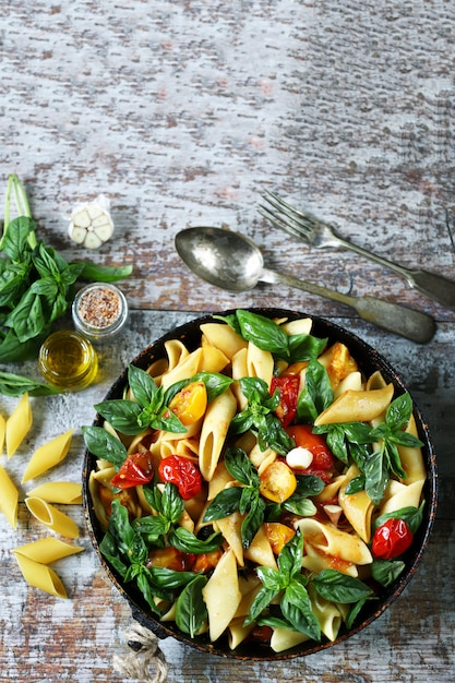 Uma panela de macarrão com manjericão. Macarrão vegano. Foco seletivo.