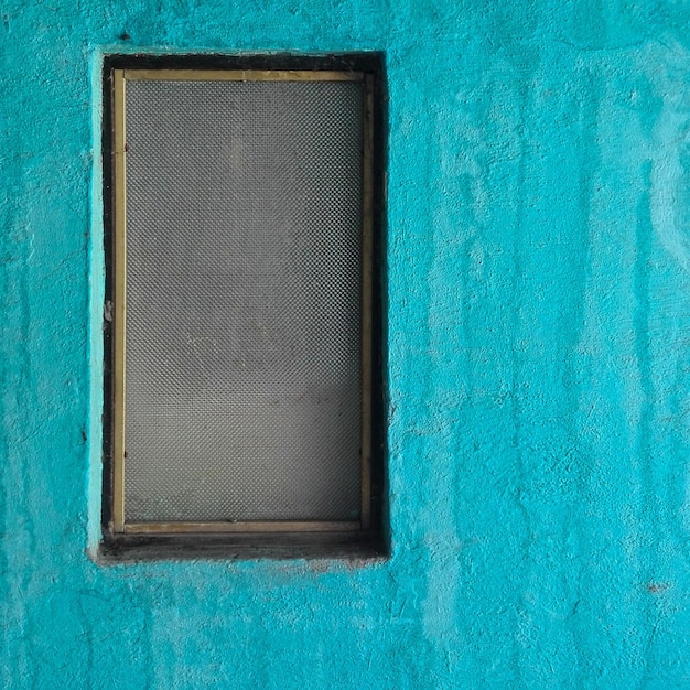 Foto uma parede azul com uma pequena janela no meio.