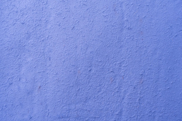 Uma parede azul é feita de gesso áspero.