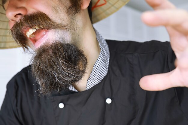 Foto uma paródia hilária de um homem asiático com um chapéu vietnamita e barba. retrato. chef do café asiático.