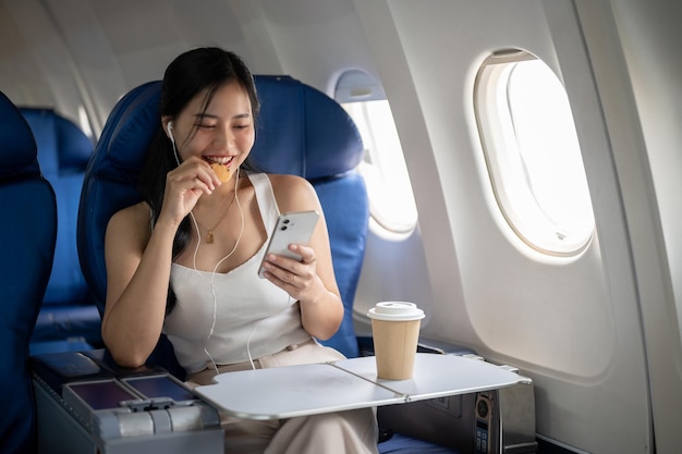 Uma passageira está desfrutando de lanches ouvindo música em seus fones de ouvido durante o voo