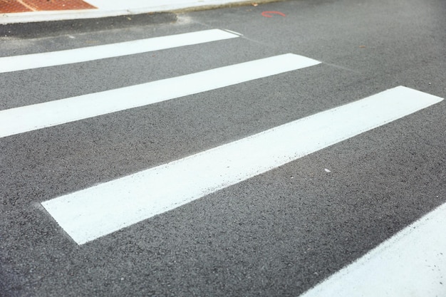 Uma passagem para pedestres branca com uma faixa branca na estrada.