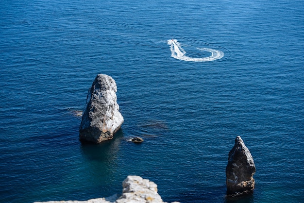 Uma pedra grande e pitoresca fica em todos os lados, cercada pela paisagem de água e mar