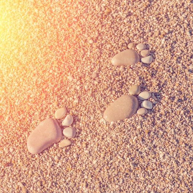 Foto uma pegada feita de pedras na areia à luz do sol.