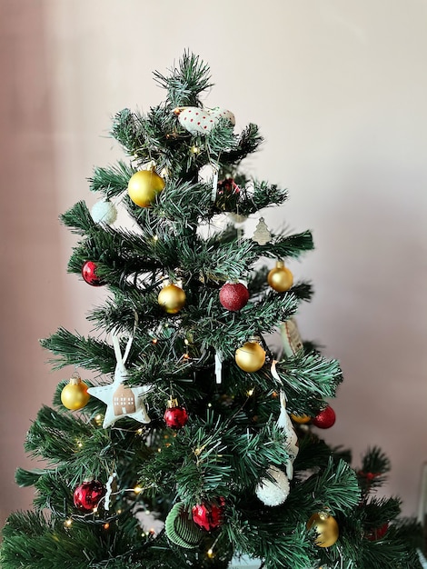 Uma pequena árvore de Natal de plástico decorada com brinquedos está no apartamento