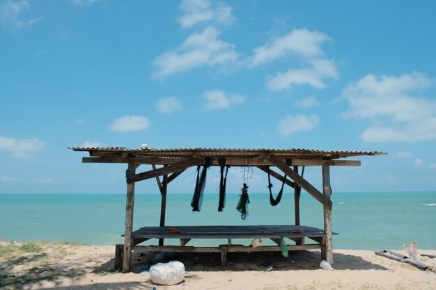 Uma pequena cabana na praia com um céu azul ao fundo.