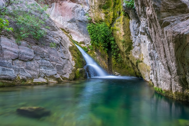 Uma pequena cachoeira pitoresca em uma aconchegante lagoa de montanha.