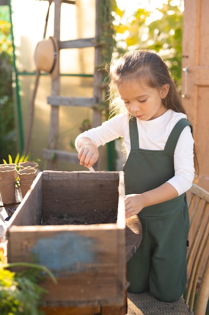 Uma pequena e bonita agricultora de cabelos compridos está empenhada em plantar plantas, jardinagem de horta de aldeia, ecologia