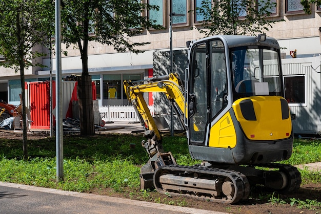 Uma pequena escavadeira amarela em um canteiro de obras na cidade