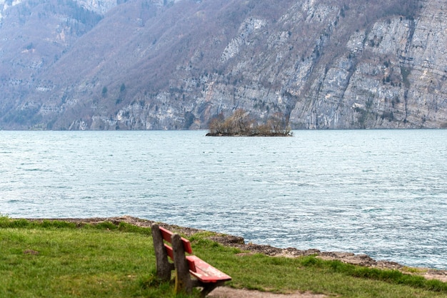 Uma pequena ilha no lago Walensee na Suíça contra um fundo de montanha rochosa