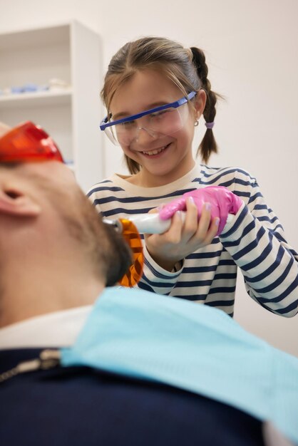 Foto uma pequena menina encaracolada e seu pai jogam um relacionamento feliz de dentista