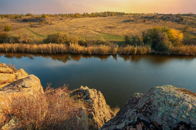 Uma pequena pilha de pedras antigas em um grande campo verde-amarelo contra o pano de fundo de um céu azul fantasticamente lindo