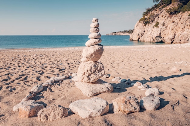 uma pequena torre de pedras como elemento decorativo em uma praia de areia junto ao mar azul-turquesa