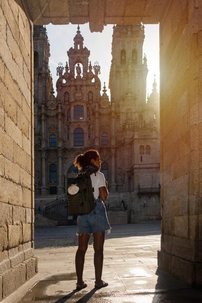 Foto uma peregrina com uma mochila entrando na praça da catedral de santiago de compostela