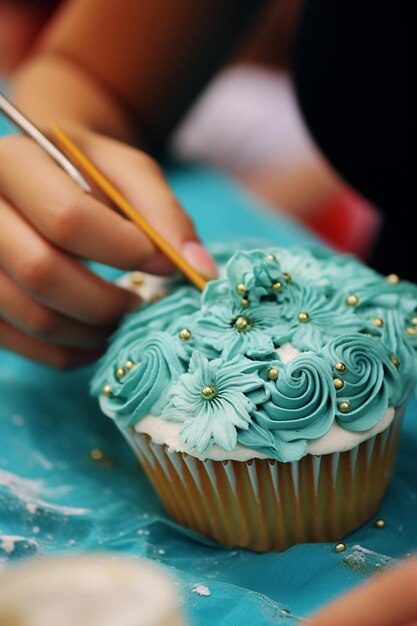 Foto uma pessoa a pintar um cupcake com cobertura azul