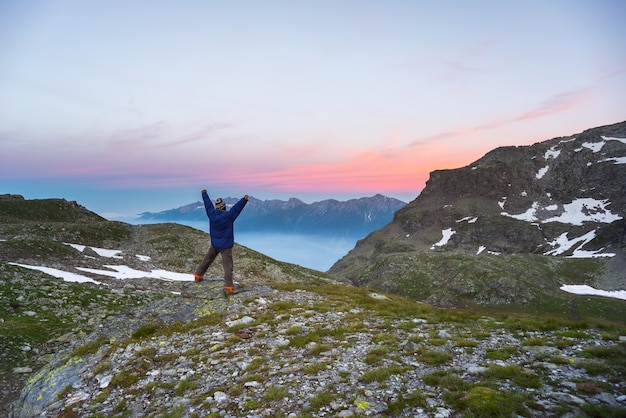 Uma pessoa assistindo o nascer do sol no alto dos alpes